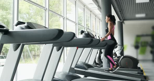 Strong Pretty Woman Training on Running Simulator in Sport Club. Athlete Female Doing Sport-walking alt