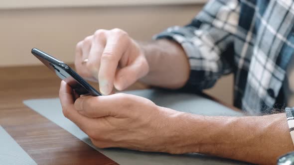 Hands of a Man with a Smartphone Closeup in the Room