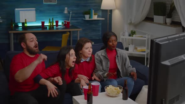 Multi Ethnic Friends Sitting in Front of Television on Couch While Watching Football alt