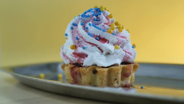 Sweet Cake with Cream and Colored Decorations with Round Balls on a Yellow Background alt