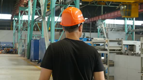 Professional Factory Worker In Hard Hat Walking Through Manufacturing Facility
