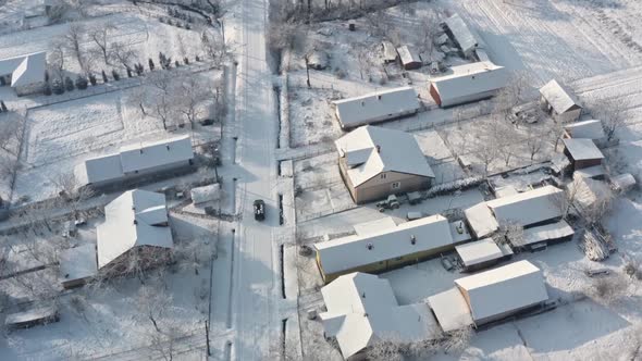Aerial Drone view of Car is driving on a snowy road, people walk. Winter season