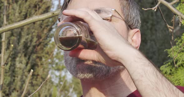 Close-up Face of Adult Caucasian Man Drinking Fresh Dark Beer Outdoors alt