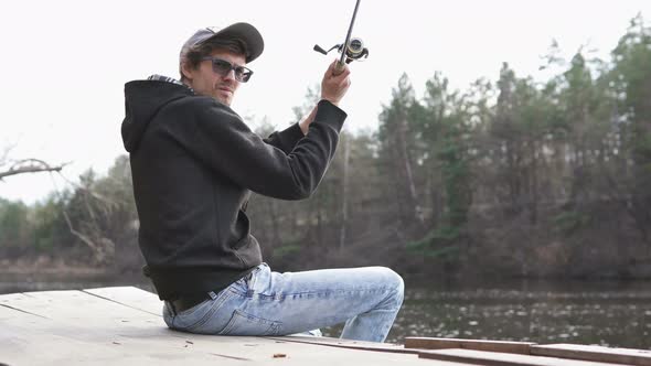 The guy in his free time catches a predatory fish on spinning from the shore. Fishing as a hobby. alt