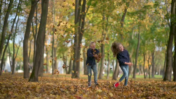 Boy and Girl Throw and Play a Fallen Leaf Slow Motion.