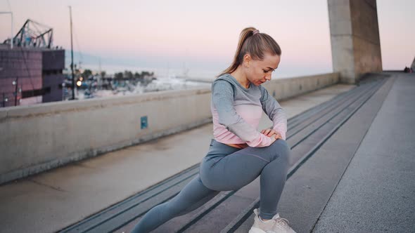 Young Athletic Female Doing Deep Lunge Exercises on Street Stairs alt