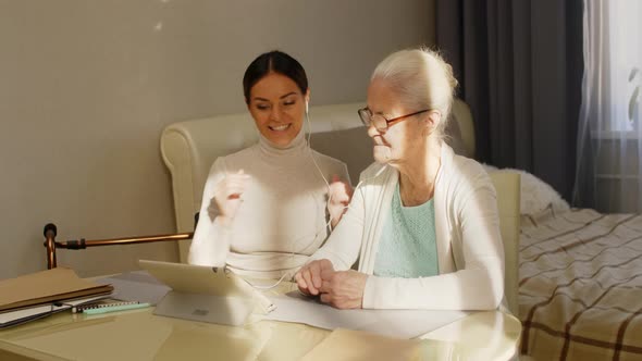 Woman Teaching Grandmother to Make Web Call on Tablet