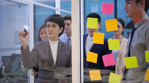 Business people with sticky notes on glass wall alt