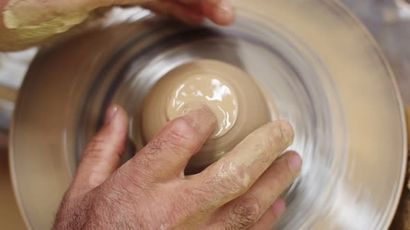 Potter Moistens Piece of Clay with Water Spinning on Potter Wheel Top View Closeup alt
