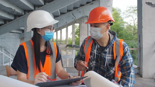 Discussion of Construction Work Between a Female Engineer and a Male Foreman in Medical Masks on the