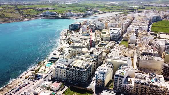 Buildings and coastline of St. Paul Bay in Malta, aerial drone view alt
