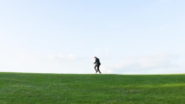 Crazy businessman dancing on a hill