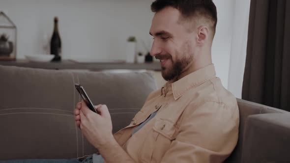 Happy Man Using Mobile Phone at Home alt