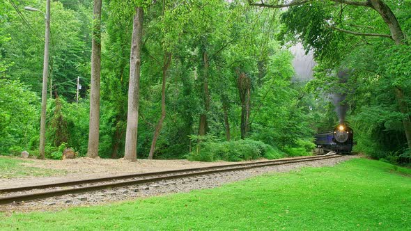 View of An Antique Steam Engine Approaching Around a Curve Traveling Thru The Woods alt