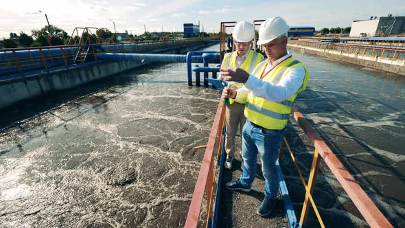 Wastewater Operators Taking a Water Sample at a Sewage Cleaning Reservoir alt