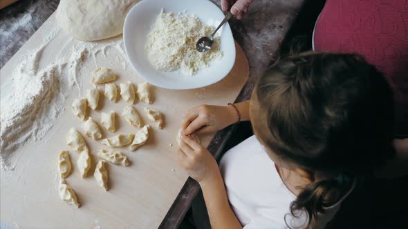 Grandmother with Granddaughter Is Making Dumplings with Cheese at Home Kitchen
