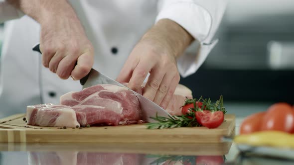 Chef Hands Cutting Meat at Kitchen. Closeup Man Chef Hands Cutting Pork Fillet alt