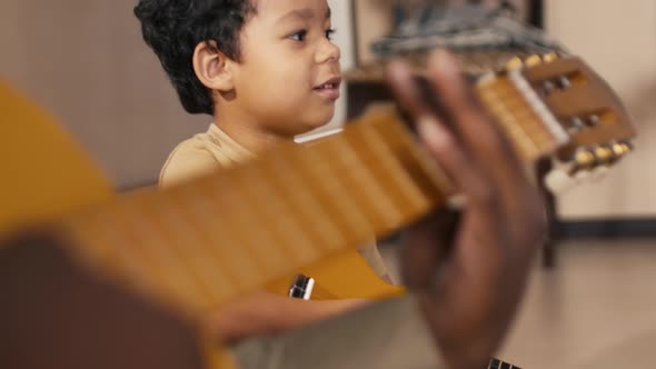 Small biracial boy imitating playing guitar and singing song