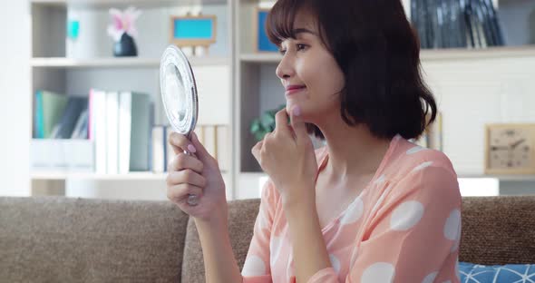 Happy smiling asian young woman looking at mirror 