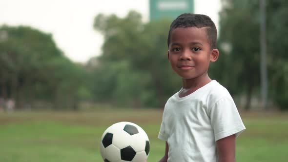 Portrait of African American boy with football, kid playing in a park alt