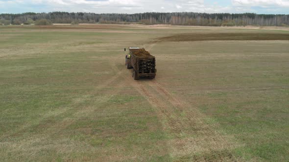 Aerial Tractor with a Manure Spreader Rides Through the Field alt