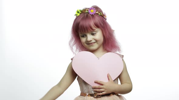 Child Girl Princess Holds Pink Paper Heart. Mothers Day, Valentines Day Concept alt