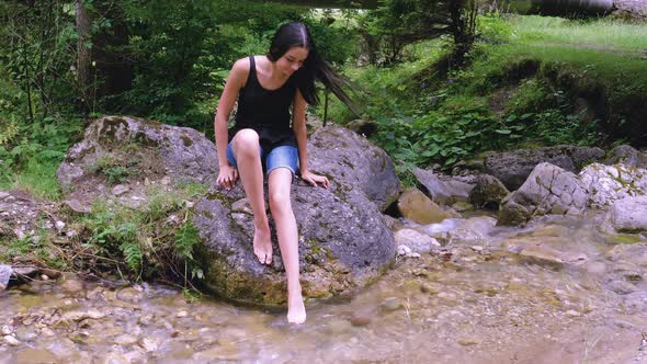 Teenage Girl Relaxing with Her Feet in River Water