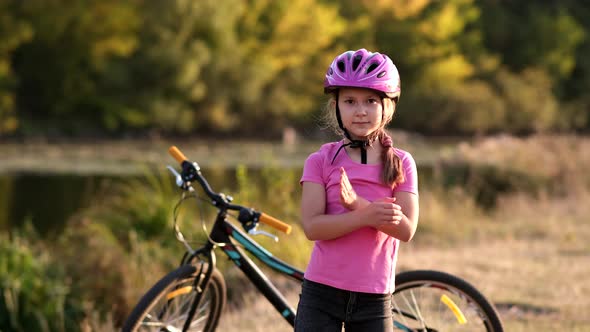 The little girl next to the bike in the helmet confidently folded her arms on her chest, 