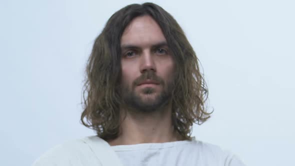Man Alike Jesus Standing on Light Background, Looking Into Camera, Messiah alt