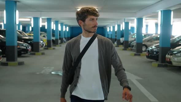 Carsharing Young Man Walks Through the Underground Parking Level a Man is Looking for a Rental Car alt