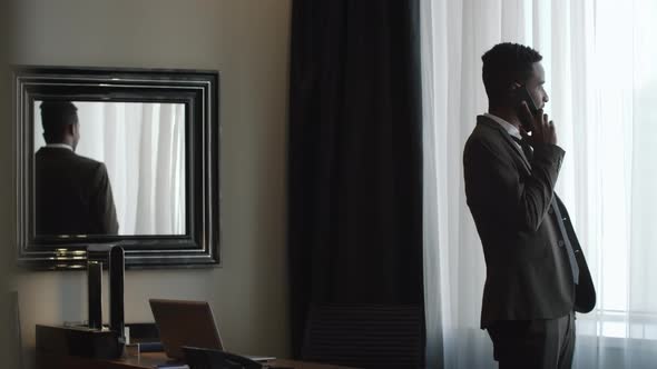 Businessman Talking on Phone in Hotel Room alt