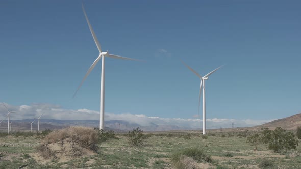 Large wind turbines spin and generate renewable electricity in a strong desert wind. alt