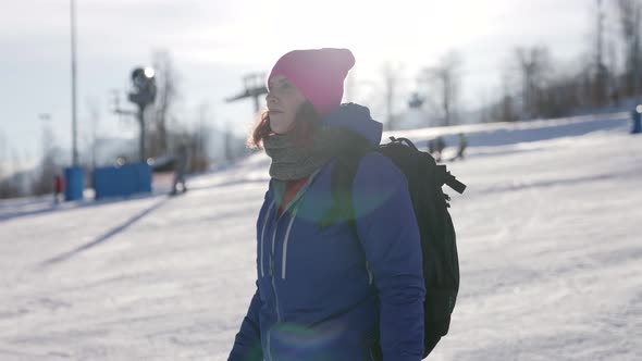 Skier or Snowboarder Woman Is Walking on Slope in Mountain Resort at Sunny Winter Day alt