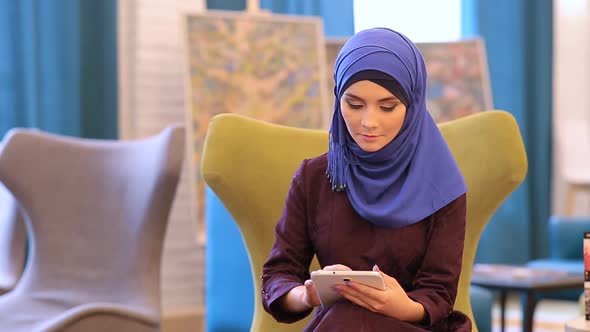 Muslim Girl In Cafe Uses Tablet