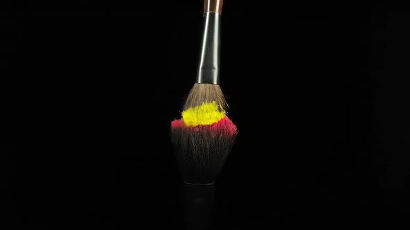 Makeup Brushes Touch Each Other on Black Dark Background and Small Particles of Color Cosmetics alt