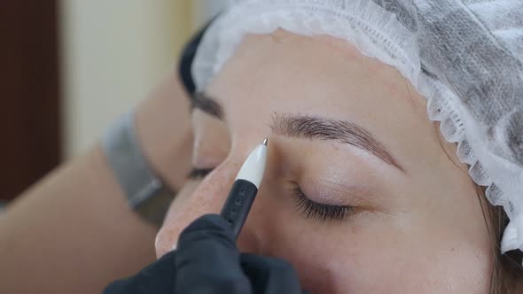 The Permanent Master Draws Lines on the Client's Face with Threads Makes a Sketch of the Eyebrows