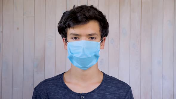 Young Man in Medical Facemask Looking at Camera. Coronavirus, Covid-19 Outbreak. Brown Eyes of 15