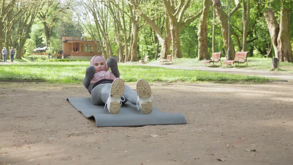 Pleasant Woman in Hijab and Sport Clothes Sitting on Yoga Mat and Stretching alt