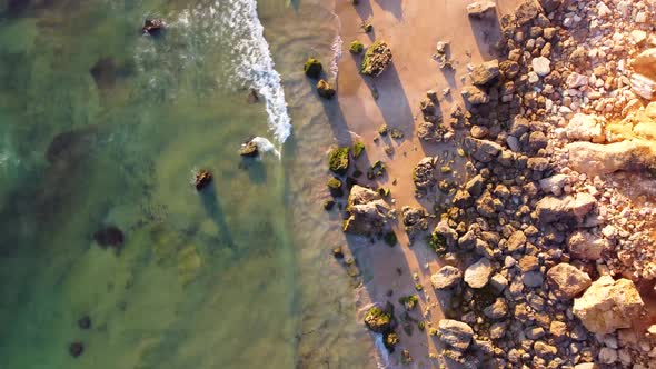 Amazing scenic drone aerial view of the beach and ocean with calm waves during a sunset