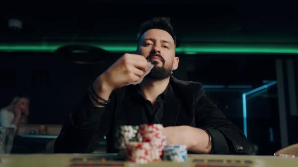 Bearded Man Is Playing Poker in Casino. Man Is Throwing His Cards on the Table alt