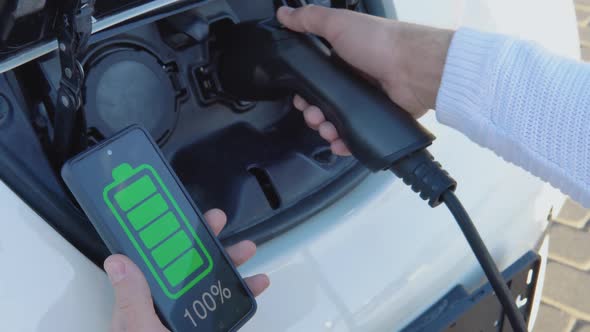 A Fairskinned Male Driver Connects an Electric Car to the Power System to Charge the Car Battery and alt