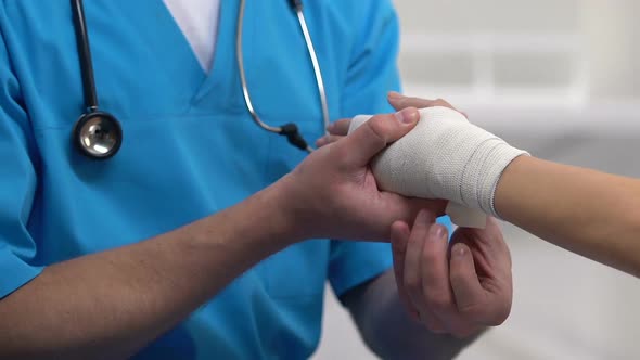 Therapist Applying Wrist Elastic Wrap to Female Patient, Sport Sprain Problem alt