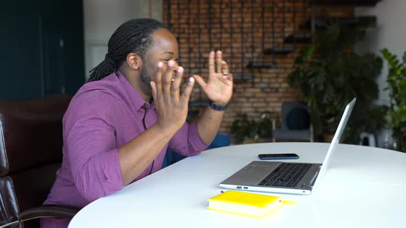 Hilarious AfricanAmerican Male Freelancer Wearing Casual Shirt Using Laptop for Video Call alt