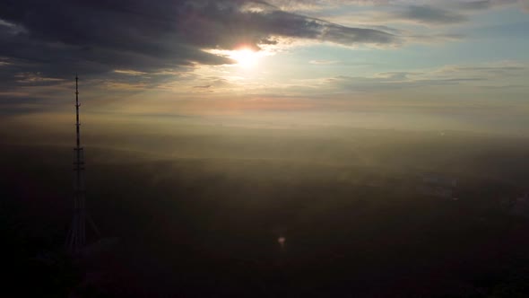 Sunrise aerial view on tv tower in cloudy forest