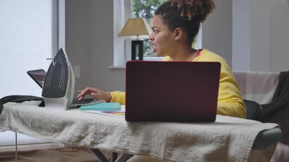 Busy Hurrying African American Woman Messaging Online on Laptop and Tablet with Stressed Facial alt