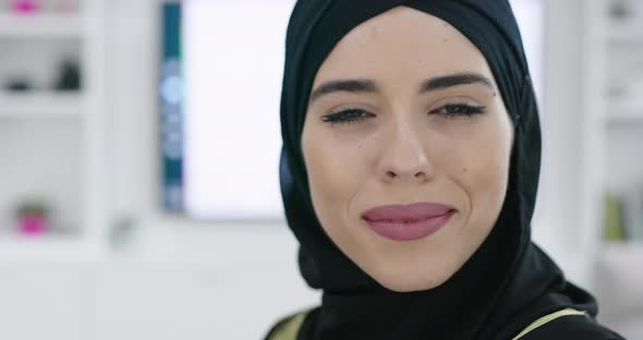 Muslim Woman Wearing Islamic Hijab Clothes Sitting on Sofa Watching TV at Jhome alt