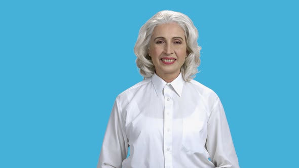 Smiling Mature Woman Giving Thumb Up on Blue Background. alt