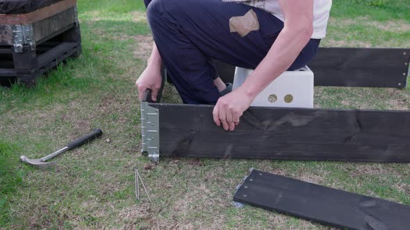 Close up view of man collecting collar of pallet for planting vegetable seeds in it. Sweden. alt