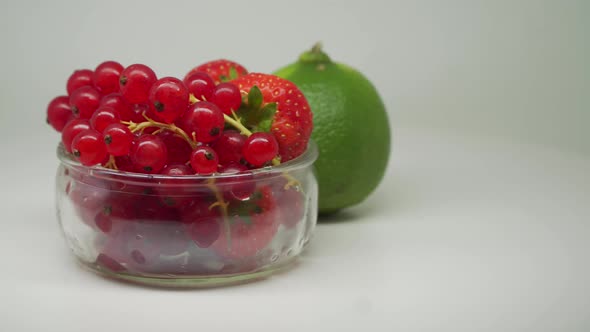 Red Cherries and Strawberries Fruit Inside The Small Transparent Bowl With Lime Outside Rotating Clo alt