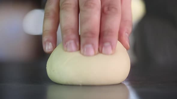 Сhef kneads dough with his hands in the kitchen